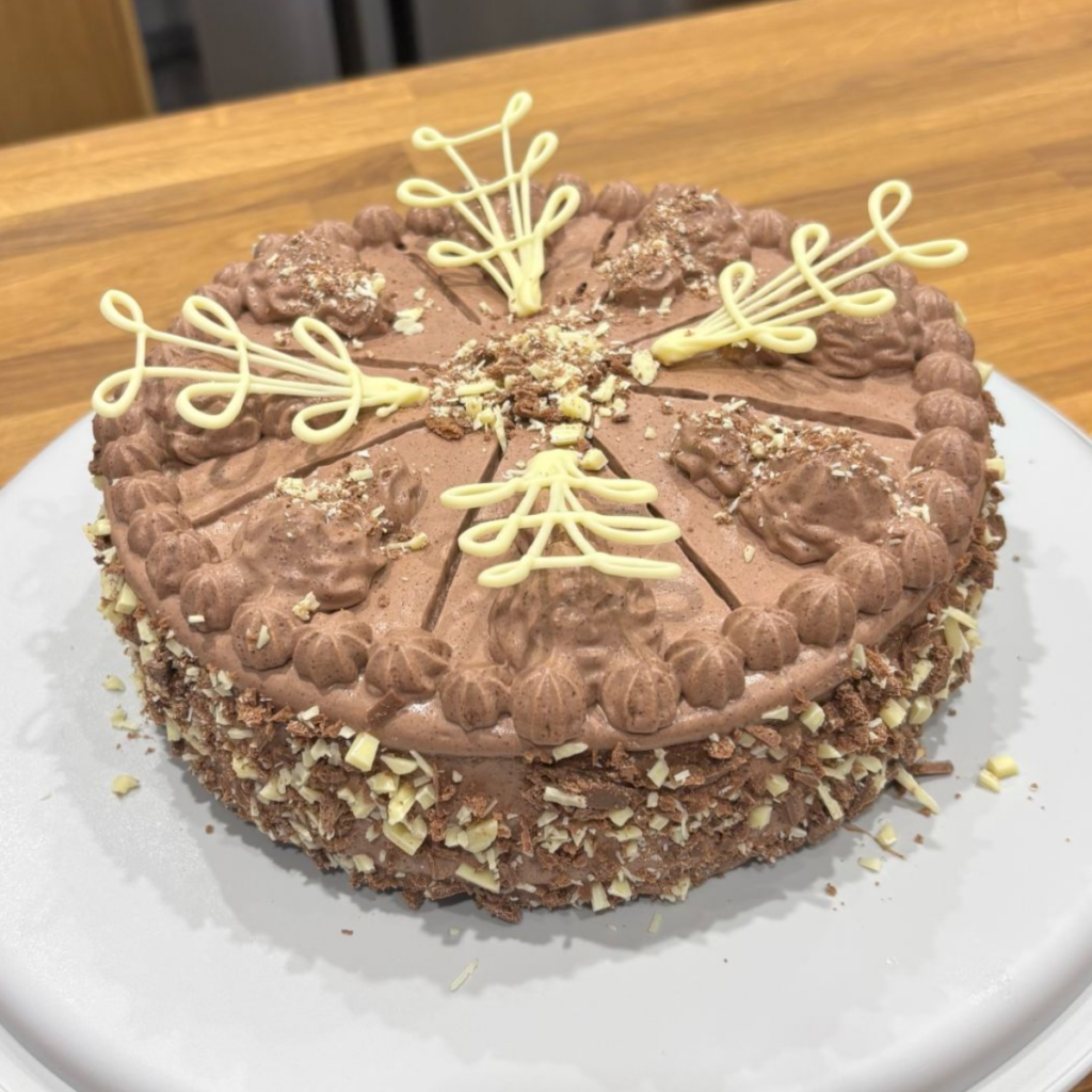 Chocolate cream cake finished with piped rosettes and chocolate shavings