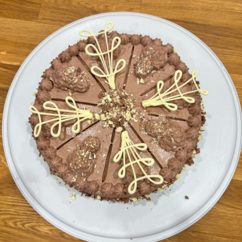 Whole German chocolate cream cake showing hand-piped white chocolate decorations