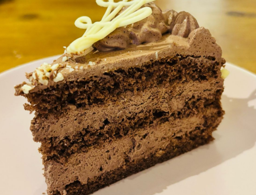 Slice of German chocolate cream cake with hand-piped white chocolate decoration