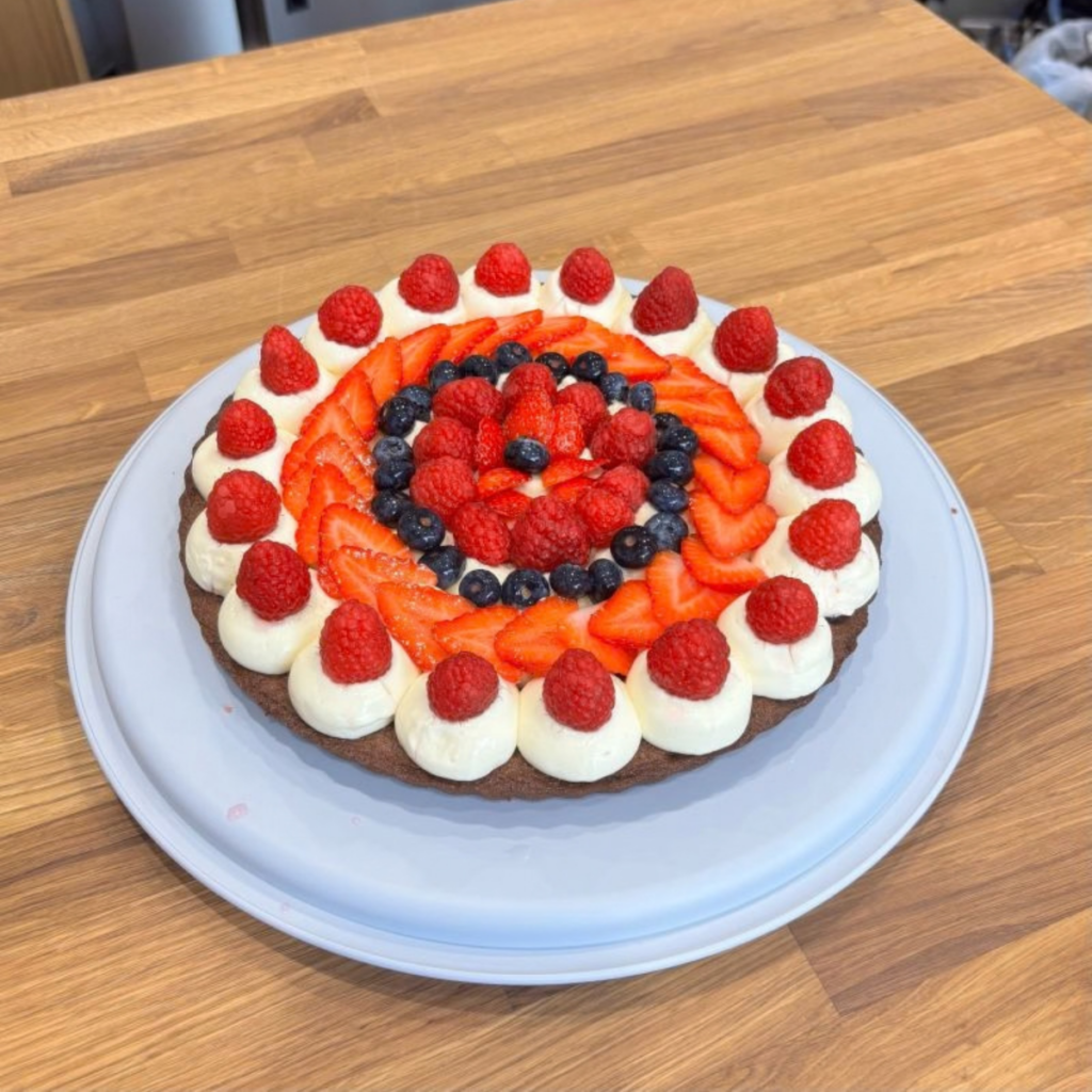 Fresh fruit flan topped with glazed strawberries, raspberries and blueberries