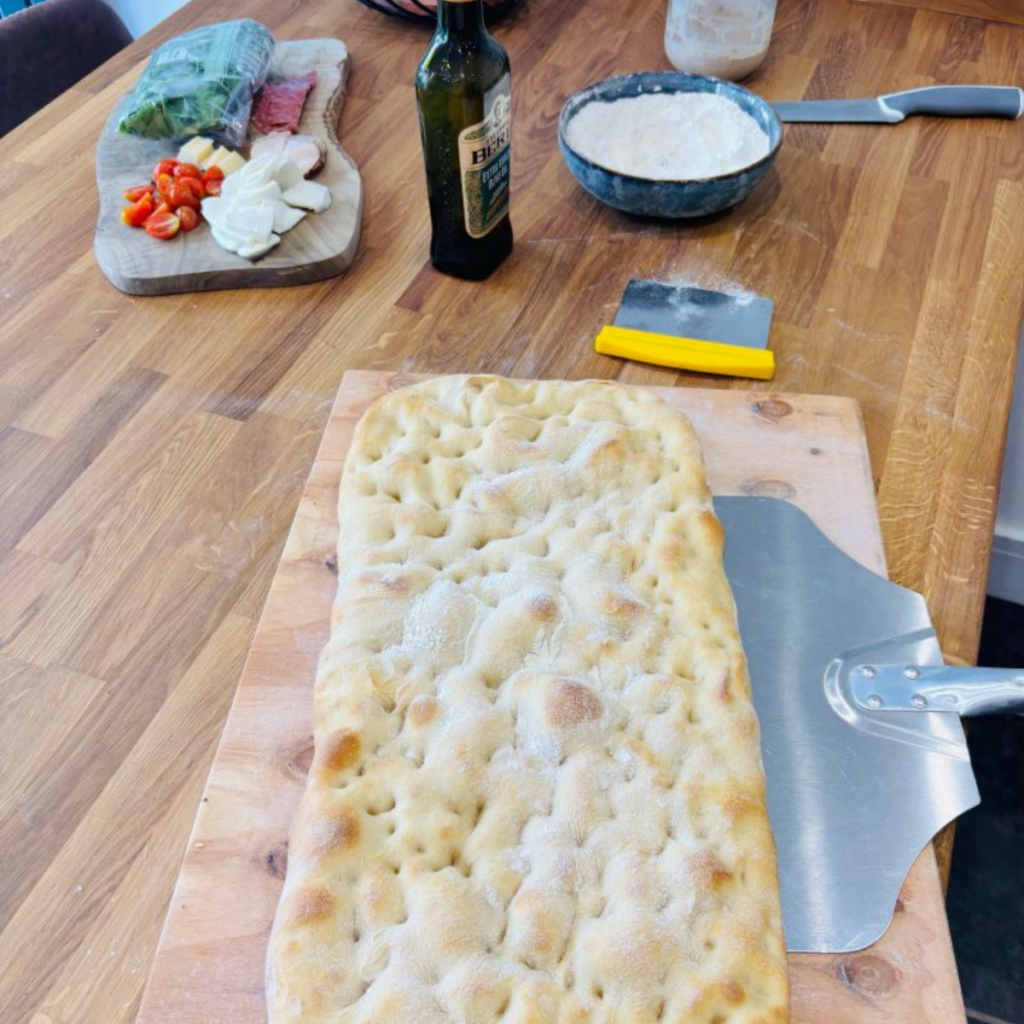 Baked Roman-style flatbread base with dimpled surface, ready to be split and filled